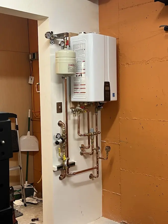 Plumbing technician inspecting water heater connections in South Weber